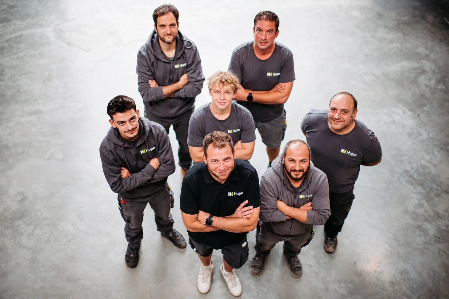 Das Team von Hupe Haustechnik von oben fotografiert, sieben Mitarbeiter mit verschränkten Armen in der Halle